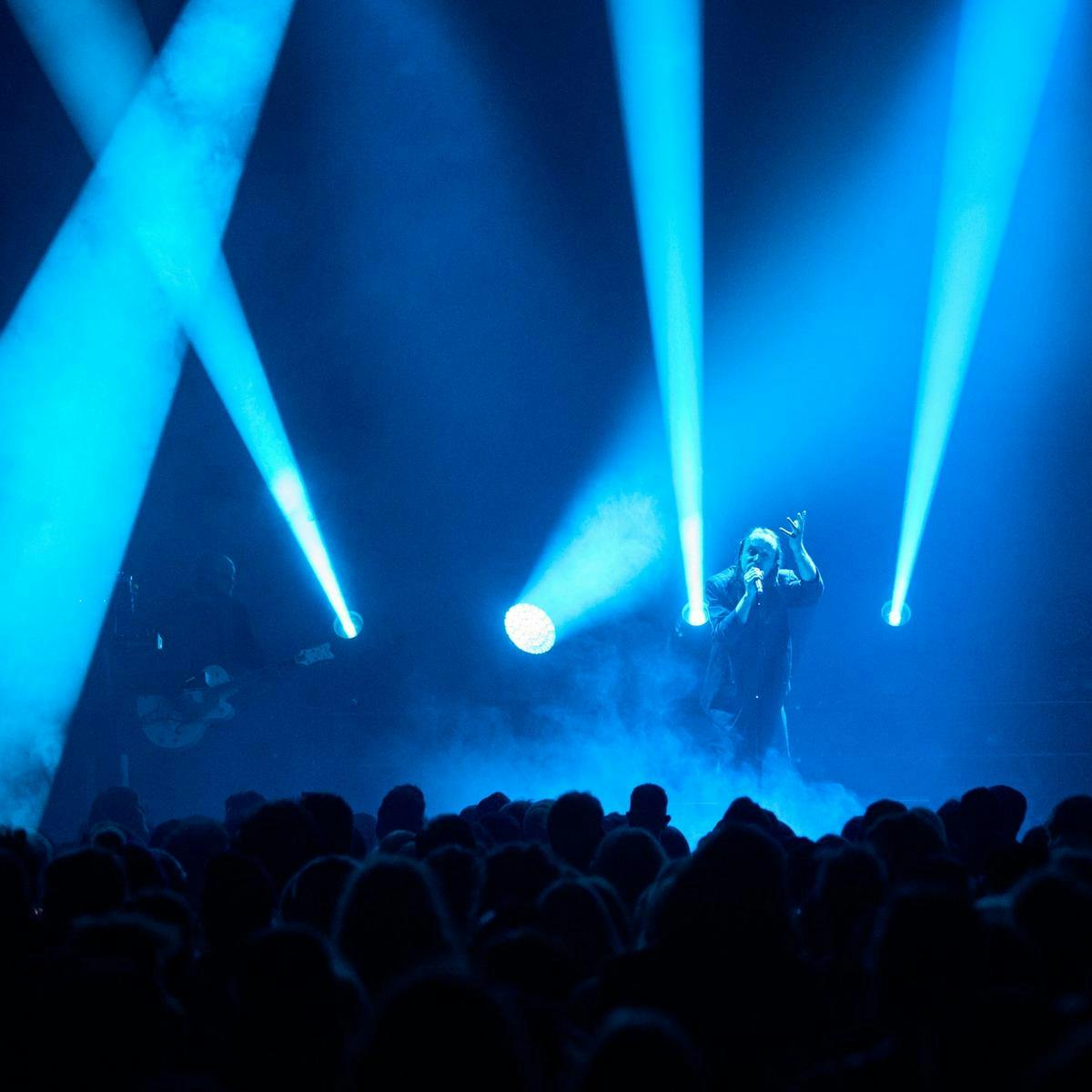 Blue beams shining up with a person singing on stage