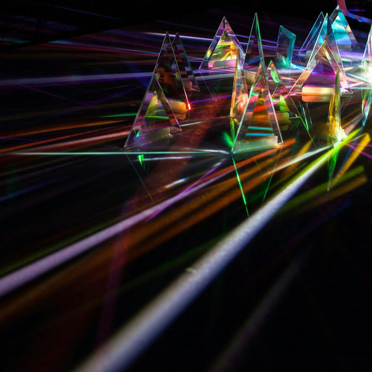 Many beams of colourful light coming from a projector, refract between several glass prisms.