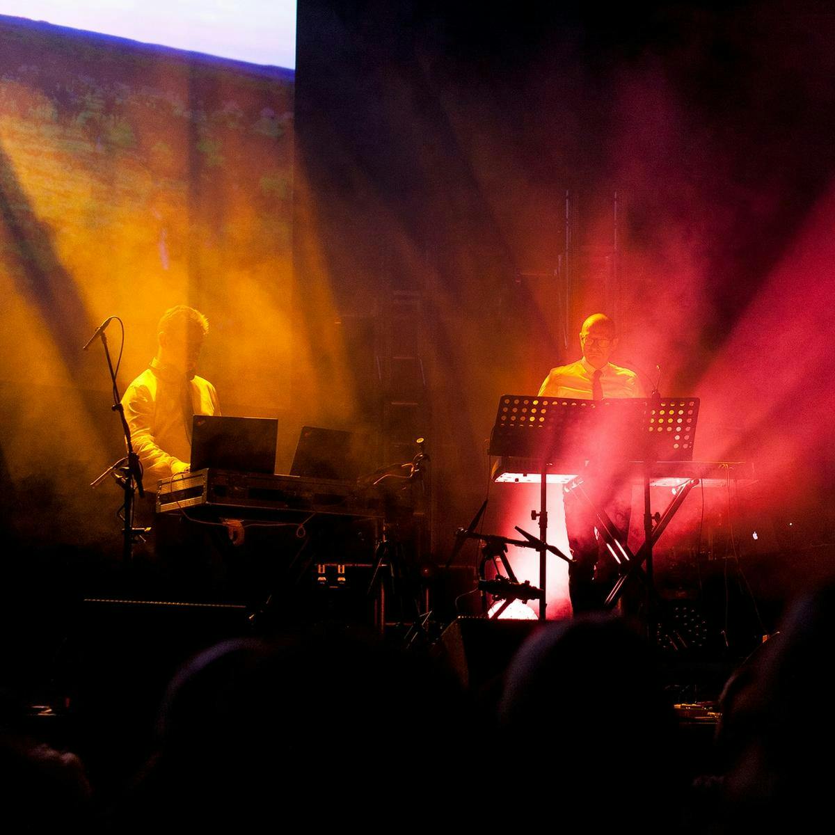 Two members of 'True North' perform on stage, wearing shirts and ties.