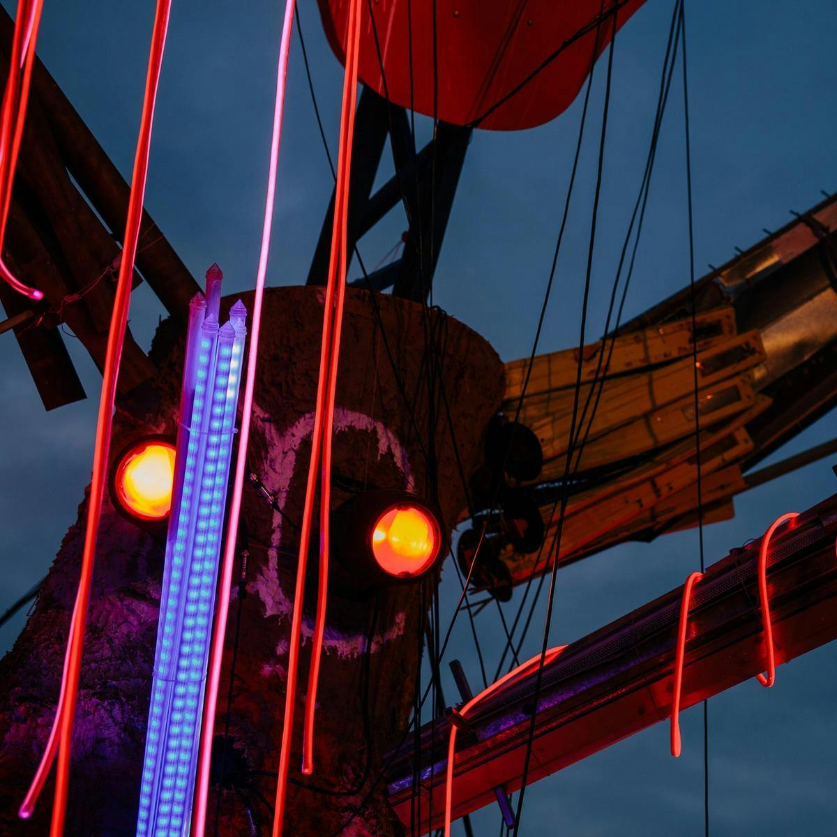 A large mixed-media sculpture made up of wood, cables, lights and metal. This is the artwork 'Earth Deities'.