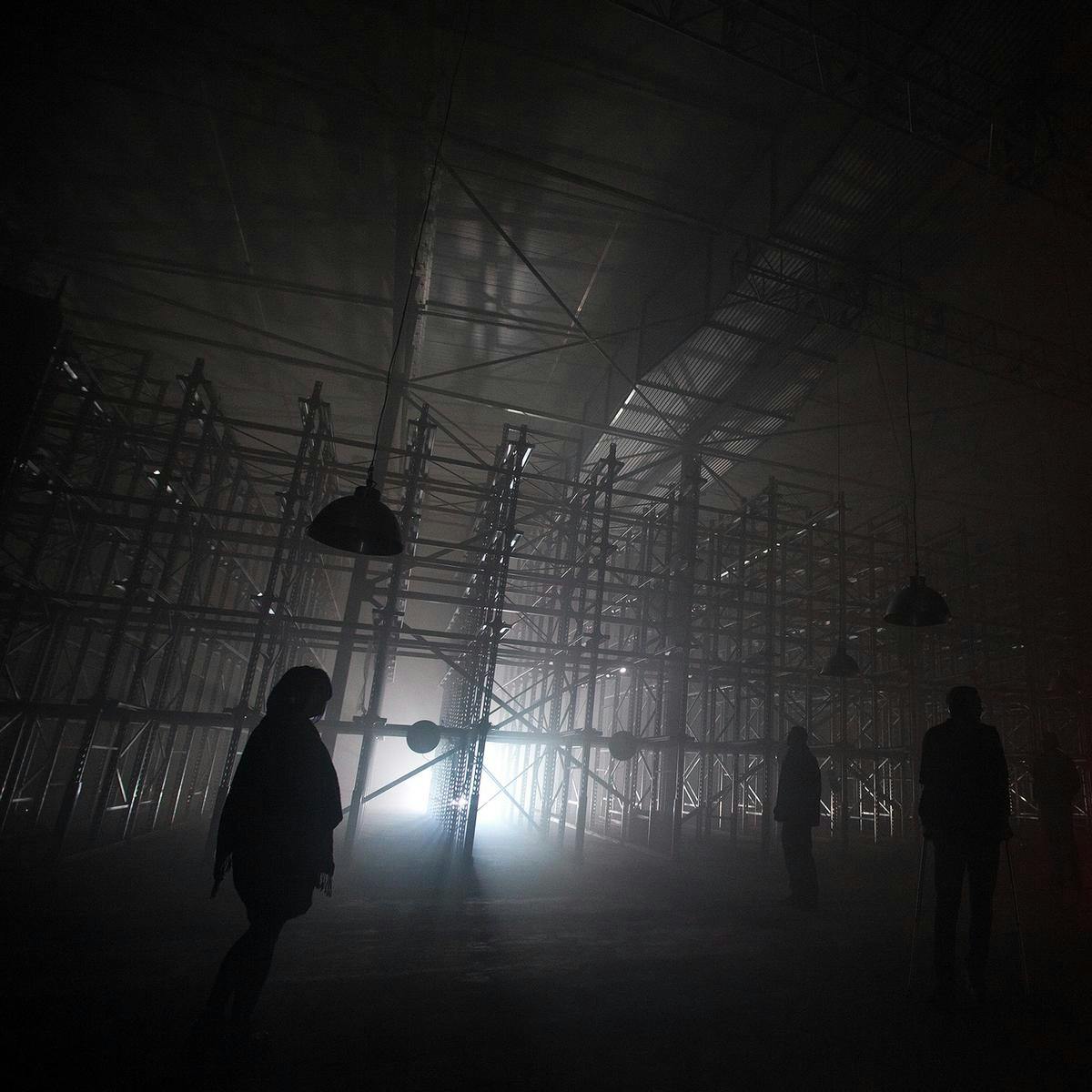 Several people wearing headphones stand at the 'Bass Bath' artwork. In the background there is a large scaffold structure.