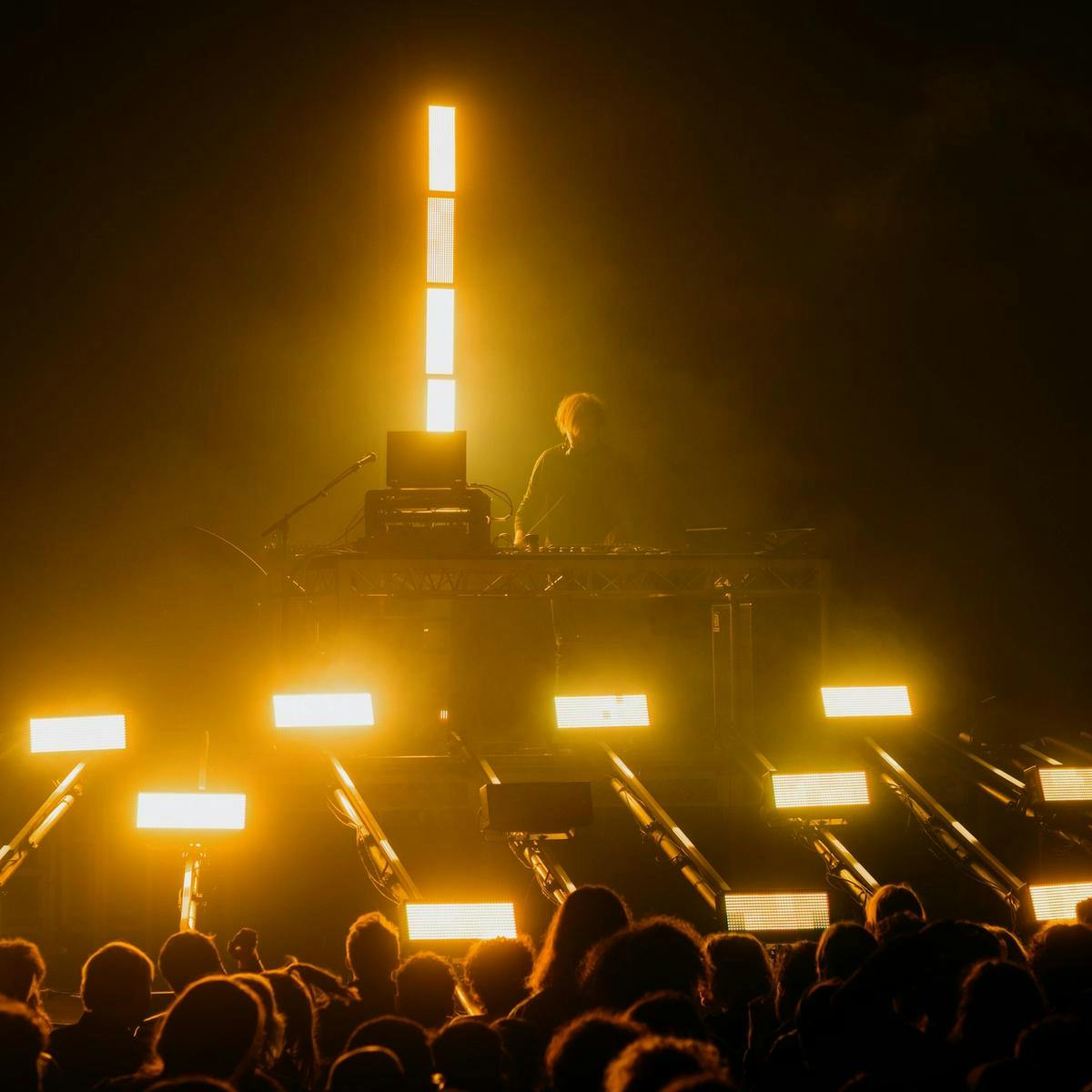 A person behind a DJ booth with yellow light squared around him