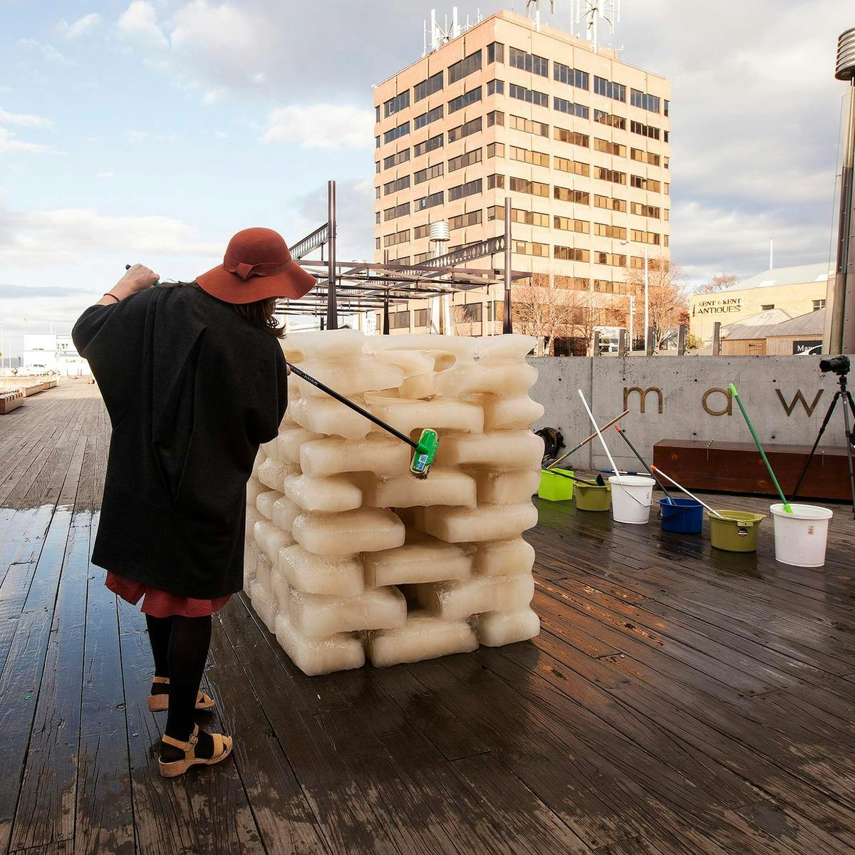 A person brushes at a block of ice, as part of the 'Washing River' artwork.