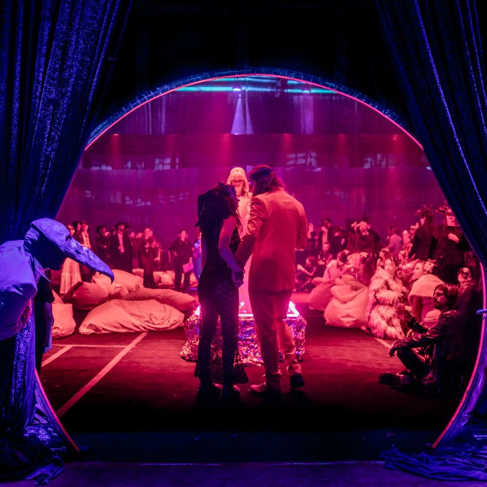 2 people peaking through a curtain looking at a wedding