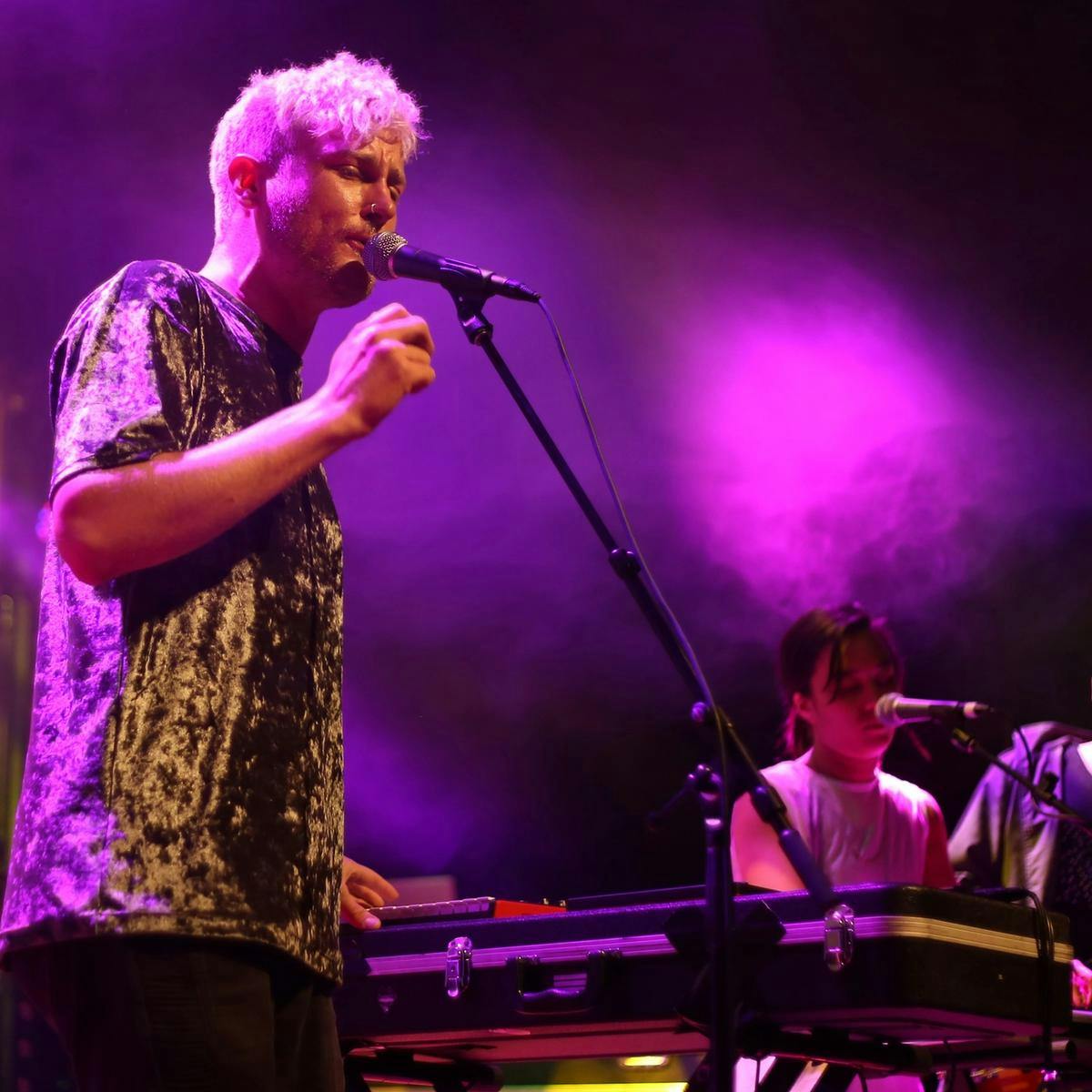 Three members of 'Tiger Choir' sing on stage.