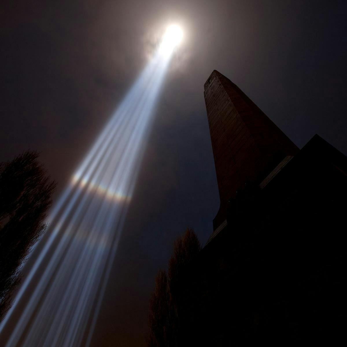 'spectra' beams high into a clouded sky, cross-sections of the light appear as rainbow.